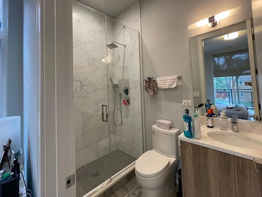 A bathroom with a white toilet, a sink, and a shower with a glass door.