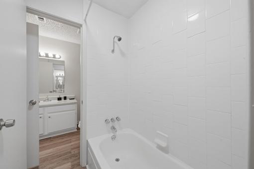 A white bathroom with a tub and a mirror.