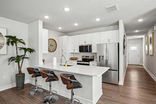 A kitchen with white cabinets and a white island with brown bar stools.