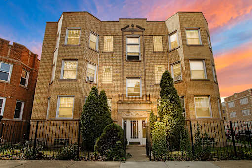 A large brick apartment building with a black fence in front.