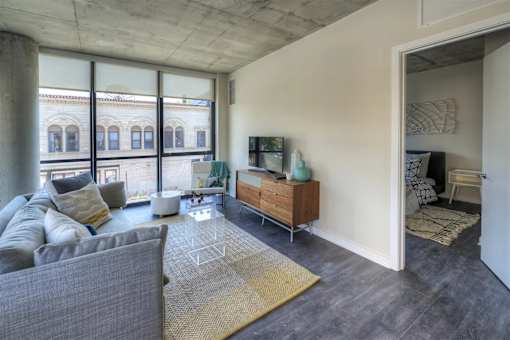 A living room with a grey couch and a wooden cabinet.