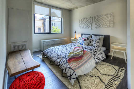A bedroom with a bed, a chair, and a window.