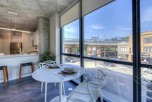 A white table with chairs is set up in a room with a view of the street outside.