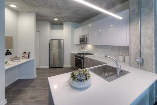 A modern kitchen with a stainless steel refrigerator and a white countertop.