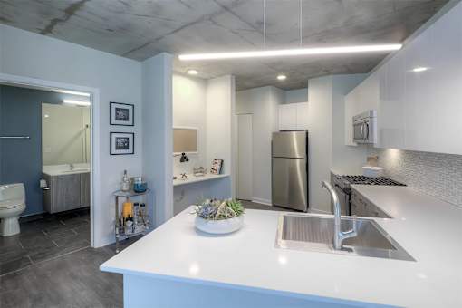 A modern kitchen with a white countertop and stainless steel appliances.