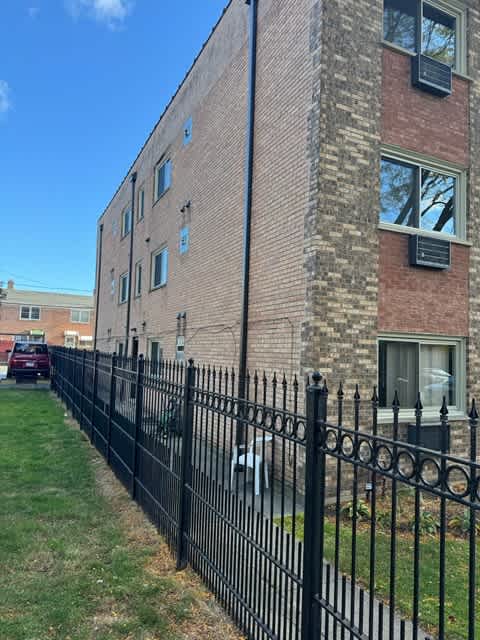 A black iron fence in front of a brick building.