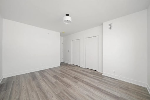 A room with a white ceiling and wooden flooring with two white doors.