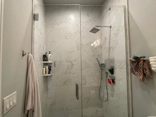 A bathroom with a marble wall and a glass shower door.
