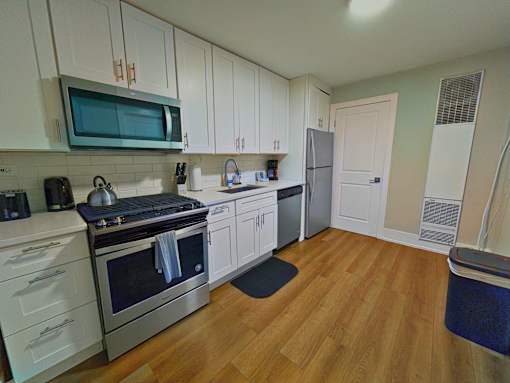 A kitchen with wooden floors and white cabinets.