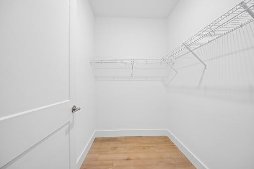 A white closet with a door and shelves.