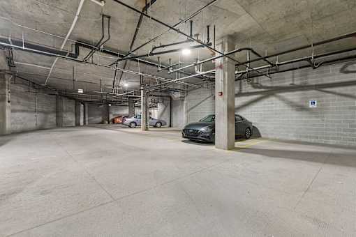 A parking garage with two cars parked.