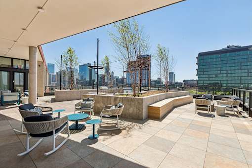 A patio with chairs and a table with a view of the city.