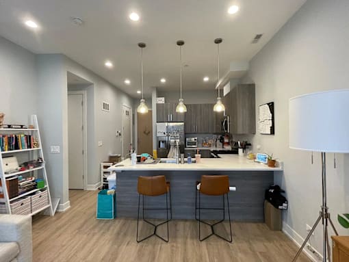 A modern kitchen with a bar area and two stools.