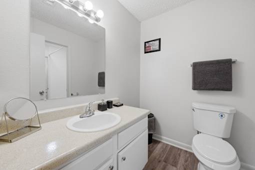 A white bathroom with a toilet, sink, and mirror.