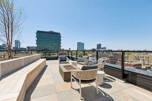 A rooftop patio with a concrete wall and a tree.