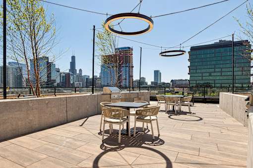 A rooftop patio with a table and chairs overlooking a city skyline.