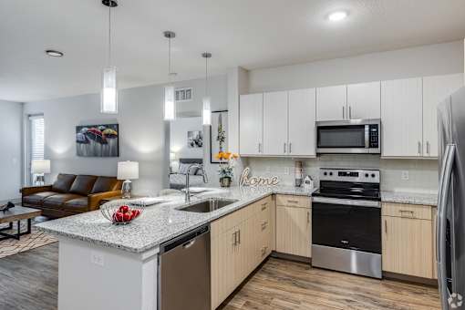 A modern kitchen with a granite countertop and stainless steel appliances.