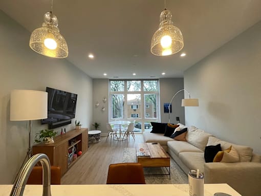 A living room with a couch, a chair, a table, a lamp, a television, and a window.