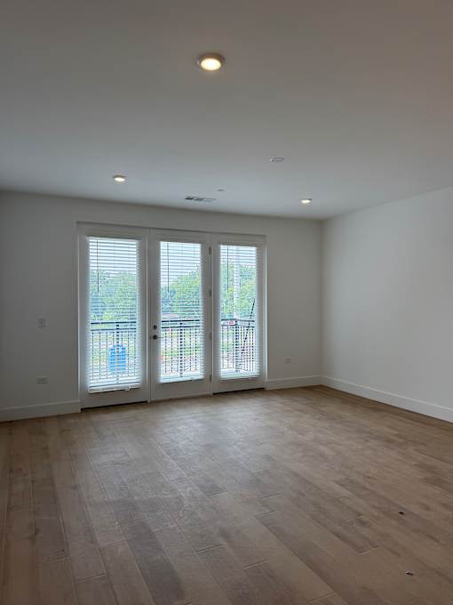 A room with a sliding glass door and wooden flooring.