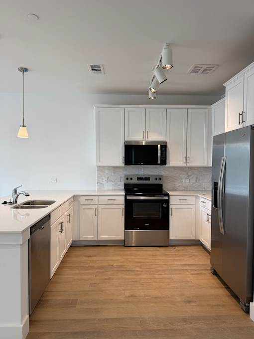 A modern kitchen with white cabinets and stainless steel appliances.