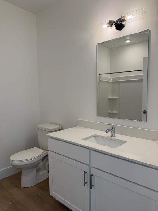A white bathroom with a toilet, sink and mirror.