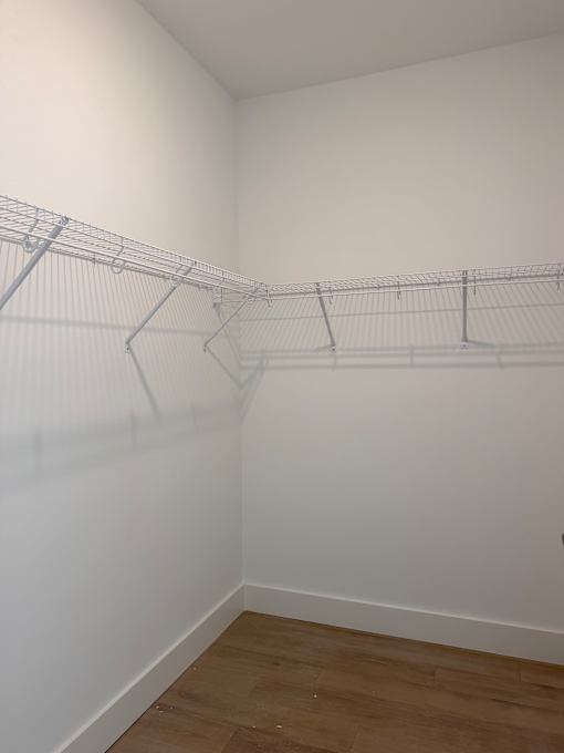 Empty room with a white wall and a wooden floor.