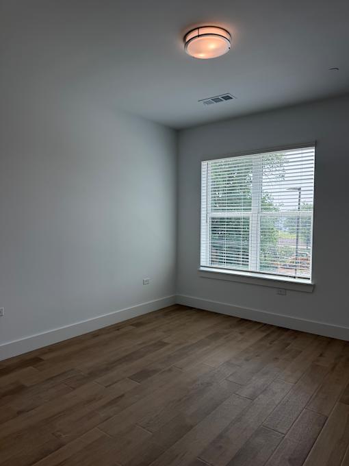 A room with a window and wooden flooring.