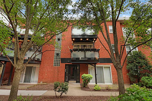 A red brick building with a balcony and a black door.
