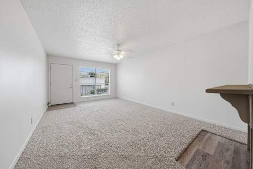 A room with a carpeted floor and a ceiling fan.