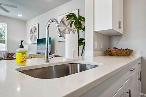 A kitchen with a white countertop and a stainless steel sink.