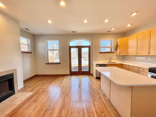 an open kitchen with a fireplace and wooden floors