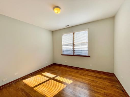 an empty room with hardwood floors and a window