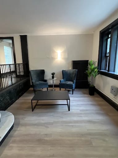 A living room with a black coffee table and two blue chairs.