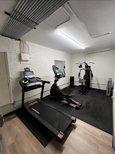 A treadmill is in a room with a mirror and a weight machine.