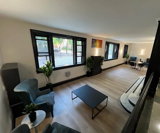 A living room with a black sofa, a grey armchair, a black coffee table, and a white couch.