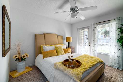 A bedroom with a white bed and yellow pillows.
