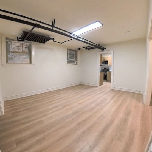 A room with wooden flooring and a window with blinds.
