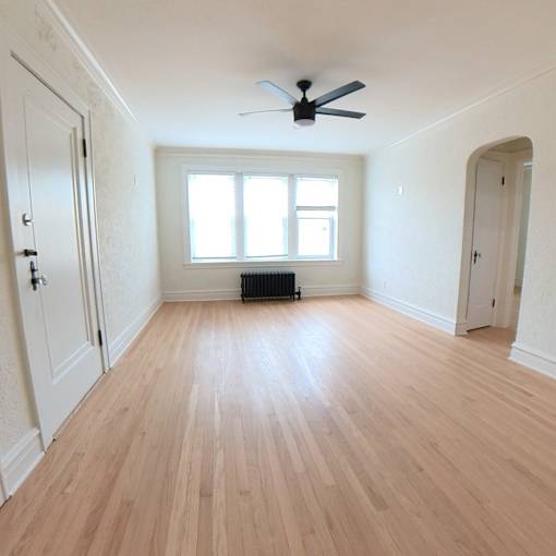 A room with wooden flooring and a ceiling fan.