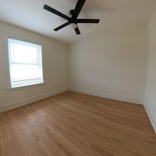 A room with a ceiling fan and a window with blinds.