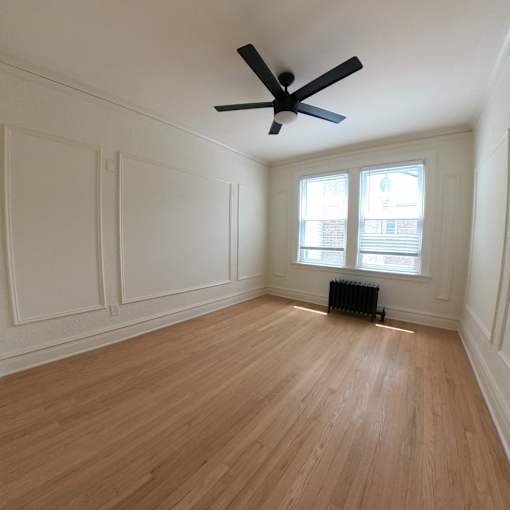 A room with a ceiling fan and wood flooring.