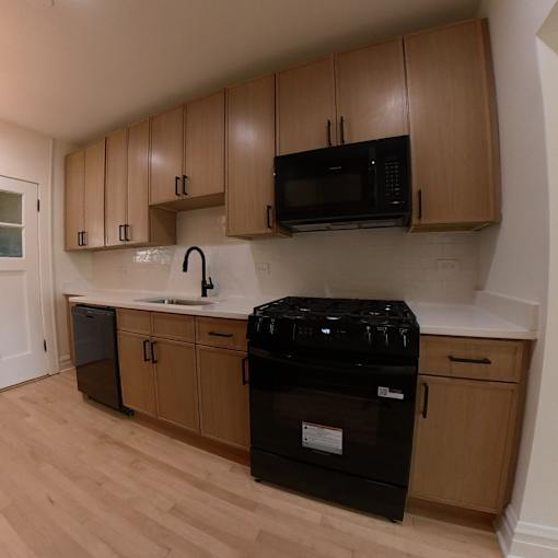 A kitchen with black appliances and wooden cabinets.
