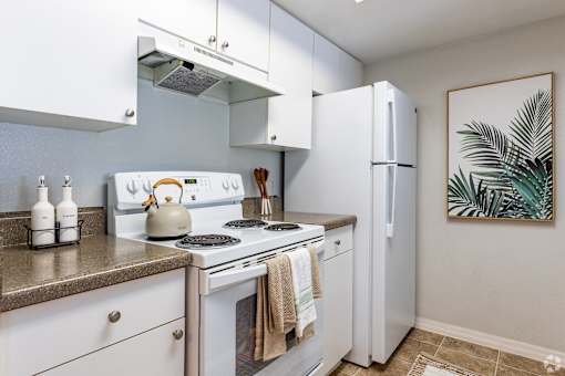 A kitchen with white appliances and a painting on the wall.
