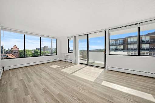 A room with a wooden floor and large windows overlooking a cityscape.