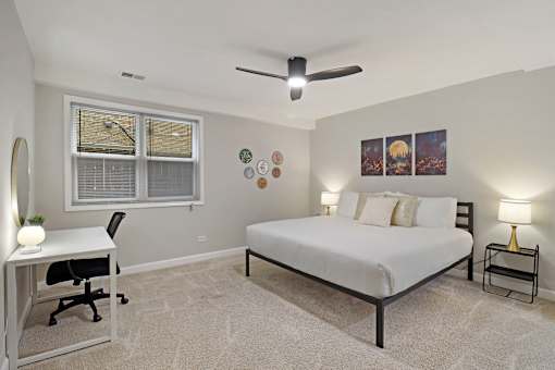 A bedroom with a bed, desk, and chair.
