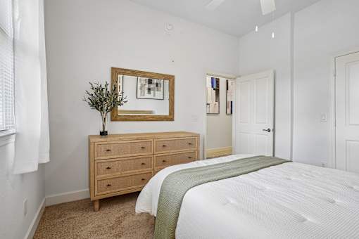 A bedroom with a bed, dresser, and mirror.