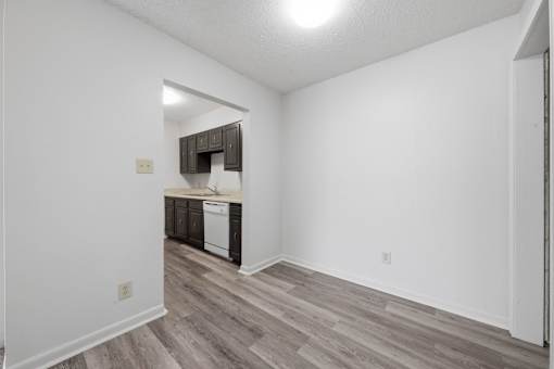 A kitchen with white walls and a wooden floor.