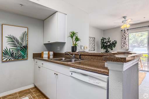 A kitchen with white cabinets and a brown countertop.
