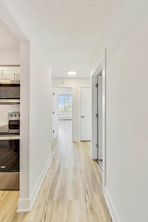 A long hallway with white walls and wood flooring.
