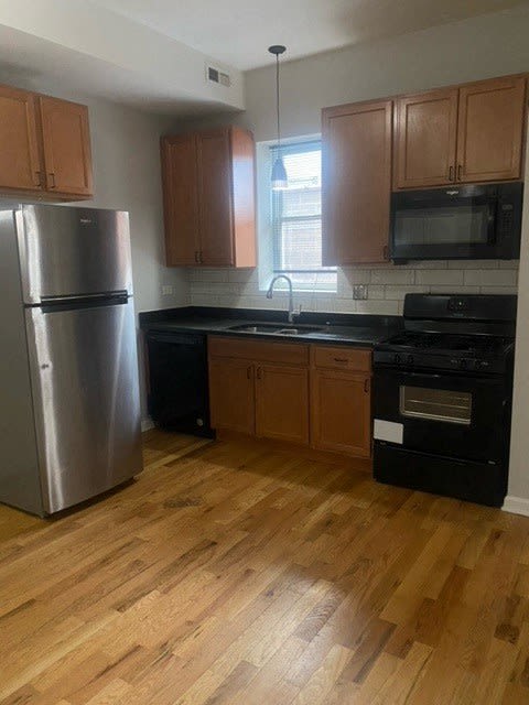 a kitchen with wooden floors and a stainless steel refrigerator
