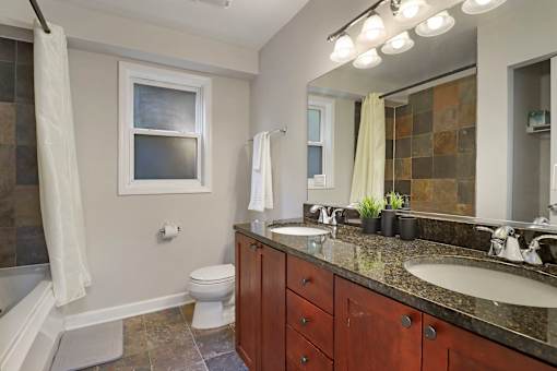 A bathroom with a toilet, sink, and mirror.